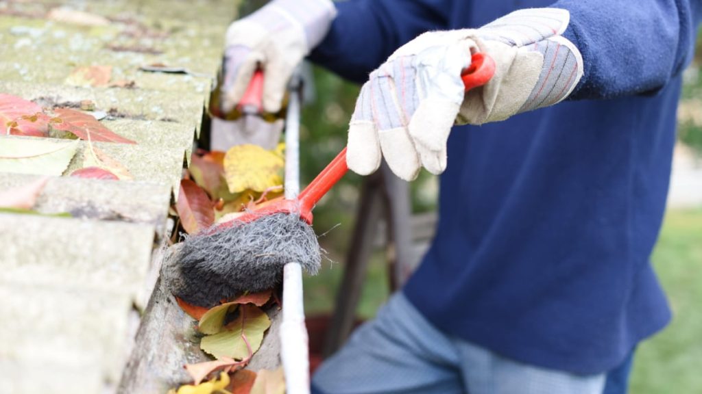 Specialist is bezig met het reinigen van de dakgoot.